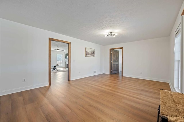 interior space with a textured ceiling, ceiling fan, and light hardwood / wood-style flooring