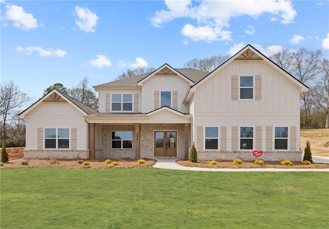 view of front facade with board and batten siding, a front yard, french doors, and brick siding