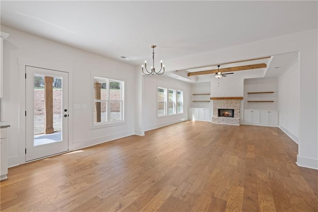 unfurnished living room with baseboards, a brick fireplace, light wood-style flooring, and ceiling fan with notable chandelier