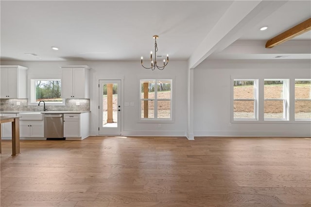 kitchen with open floor plan, dishwasher, light wood-type flooring, light countertops, and decorative backsplash