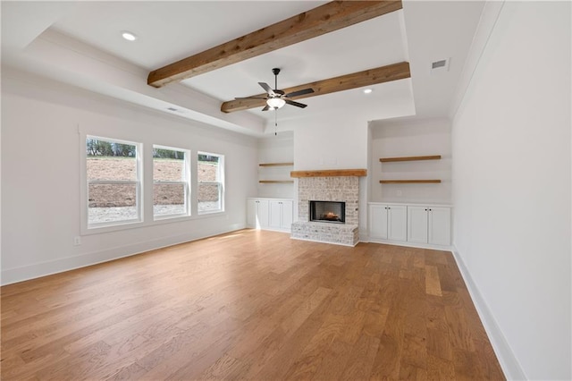 unfurnished living room featuring visible vents, a fireplace, baseboards, and wood finished floors