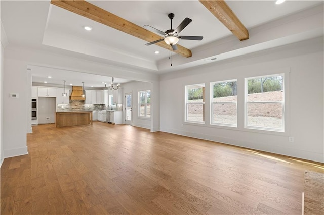 unfurnished living room featuring baseboards, light wood finished floors, beam ceiling, recessed lighting, and ceiling fan with notable chandelier