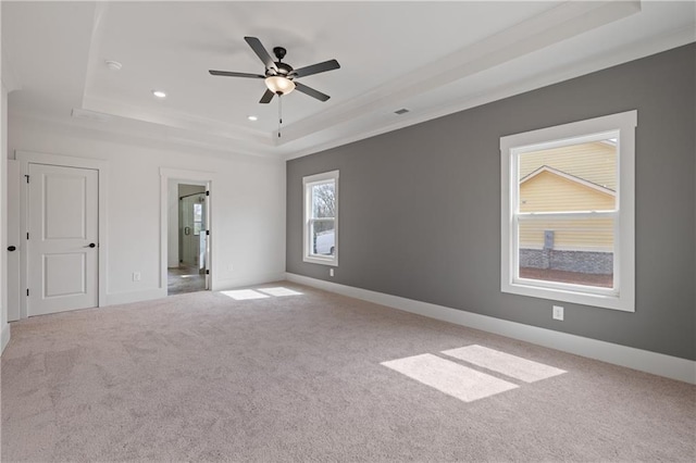 empty room with carpet flooring, visible vents, baseboards, and a tray ceiling