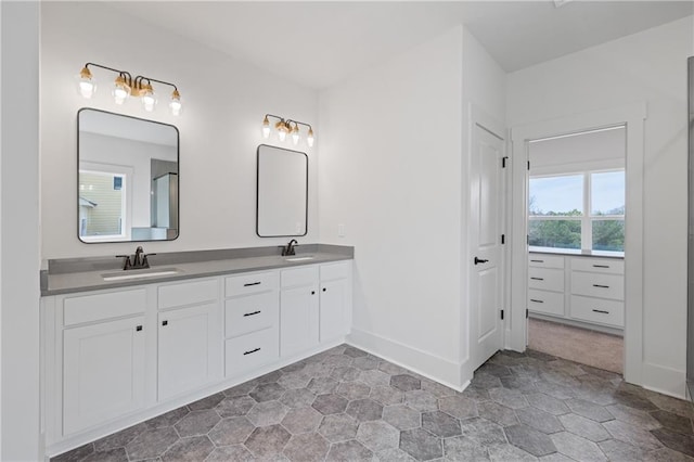 full bath featuring a sink, baseboards, and double vanity