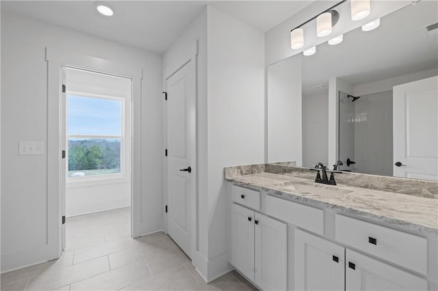 full bathroom with tile patterned floors, visible vents, a tile shower, baseboards, and vanity