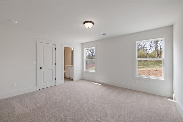 spare room with carpet flooring, baseboards, and visible vents