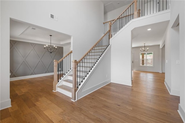 stairway featuring an inviting chandelier, wood finished floors, and baseboards