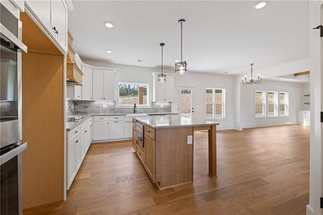 kitchen featuring tasteful backsplash, a kitchen island, oven, and light wood-style floors