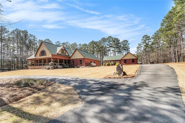 view of front of house featuring covered porch, a front lawn, and aphalt driveway