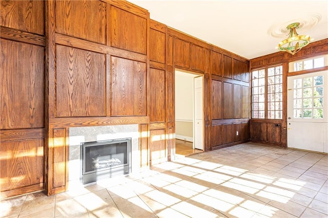 unfurnished living room with wooden walls, light tile patterned floors, and a tile fireplace