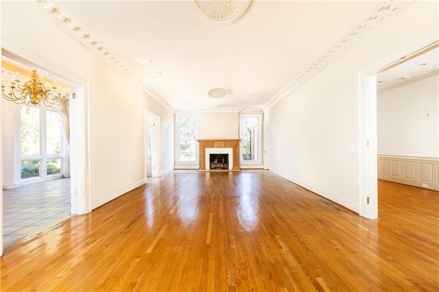 unfurnished living room featuring wood-type flooring, an inviting chandelier, and plenty of natural light