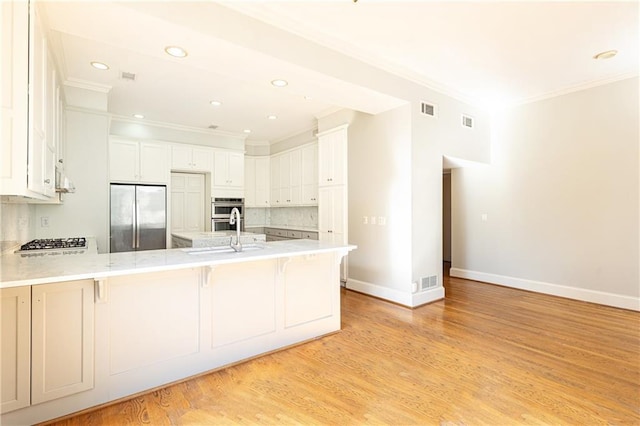 kitchen featuring a breakfast bar area, kitchen peninsula, white cabinetry, and appliances with stainless steel finishes