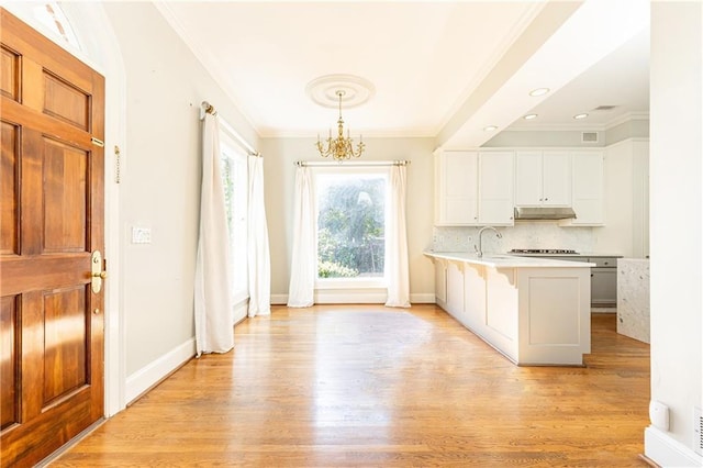 kitchen with a kitchen breakfast bar, a notable chandelier, backsplash, decorative light fixtures, and white cabinets