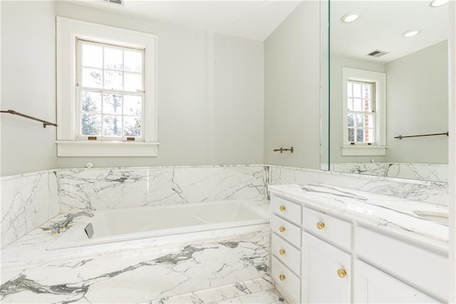 bathroom featuring vanity and a relaxing tiled tub