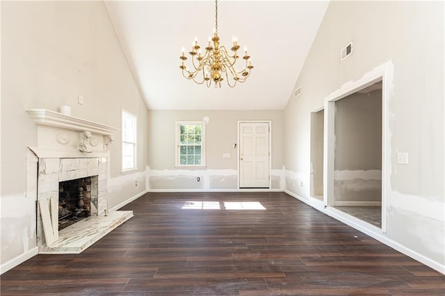 unfurnished living room with dark hardwood / wood-style floors, a fireplace, high vaulted ceiling, and an inviting chandelier