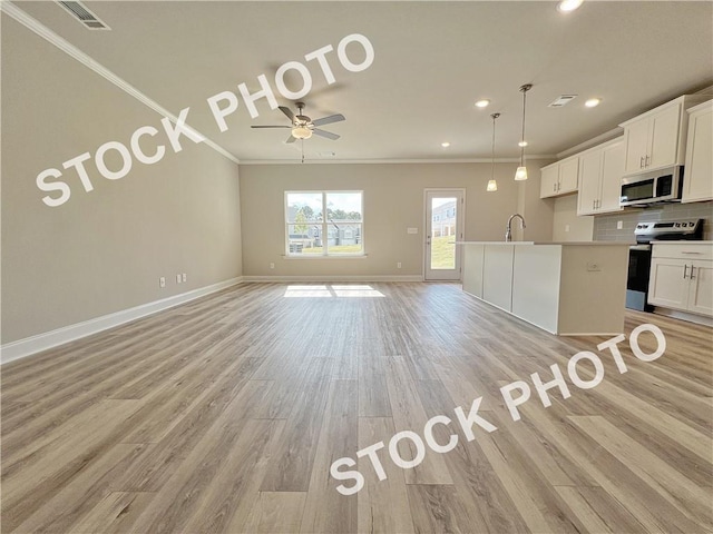 kitchen with light wood finished floors, stainless steel appliances, visible vents, decorative backsplash, and ornamental molding