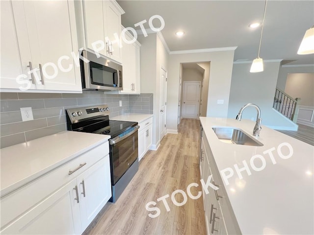 kitchen with stainless steel appliances, tasteful backsplash, light wood-style floors, ornamental molding, and a sink