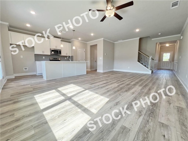 unfurnished living room with stairway, light wood-style flooring, visible vents, and crown molding