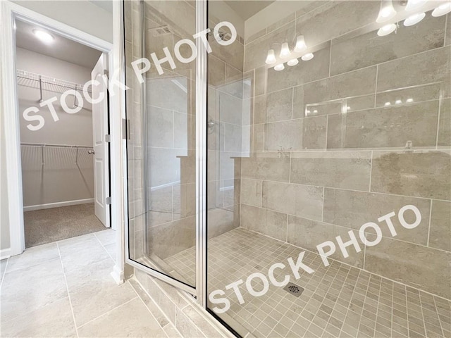 full bathroom featuring a stall shower, a spacious closet, and tile patterned floors