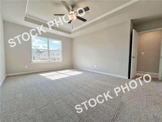 carpeted empty room with ornamental molding, a tray ceiling, a ceiling fan, and baseboards