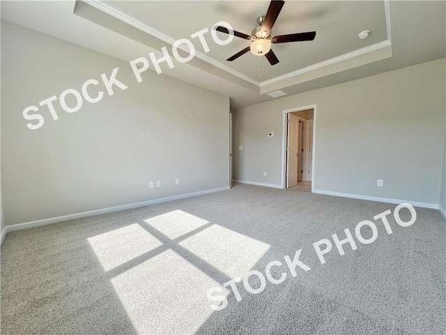 unfurnished bedroom featuring ceiling fan, carpet floors, baseboards, a raised ceiling, and crown molding