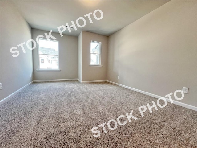 carpeted empty room featuring baseboards