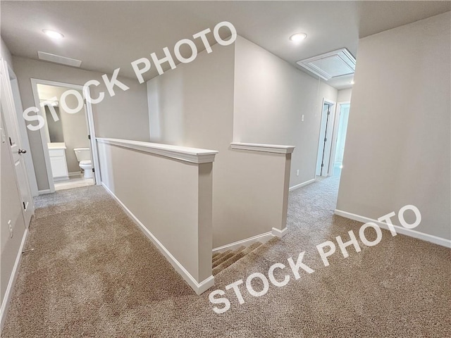 hall with attic access, baseboards, carpet flooring, and an upstairs landing