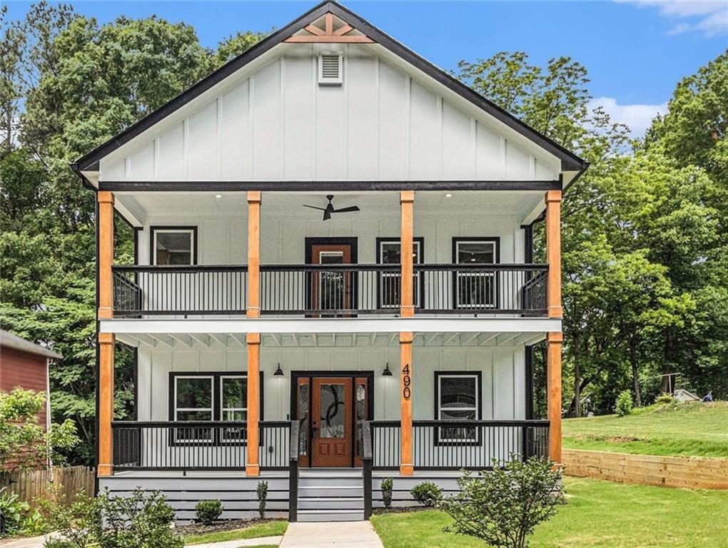 view of front facade with a balcony, covered porch, board and batten siding, and a front yard