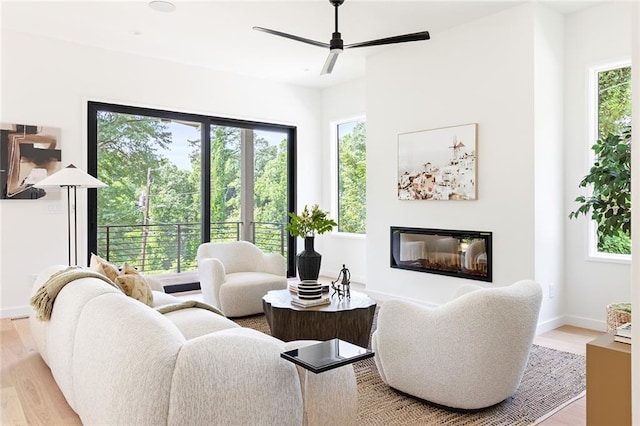 3117 Robinson Ave, Scottdale, GA 30079 - living area featuring light wood finished floors, a ceiling fan, a glass covered fireplace, and baseboards