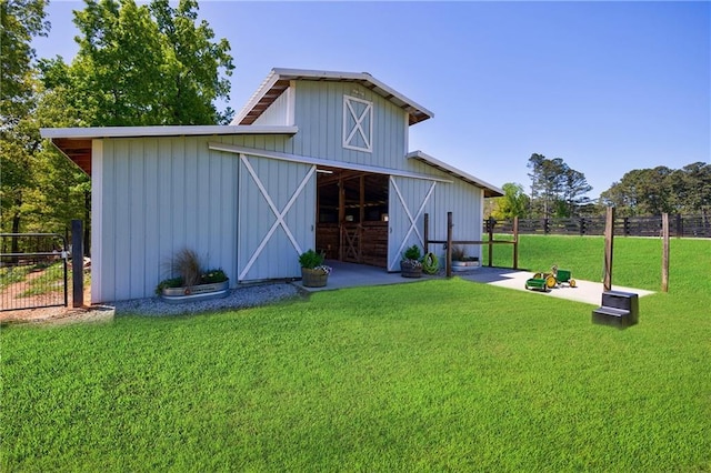 back of house featuring fence, an outdoor structure, board and batten siding, and a barn