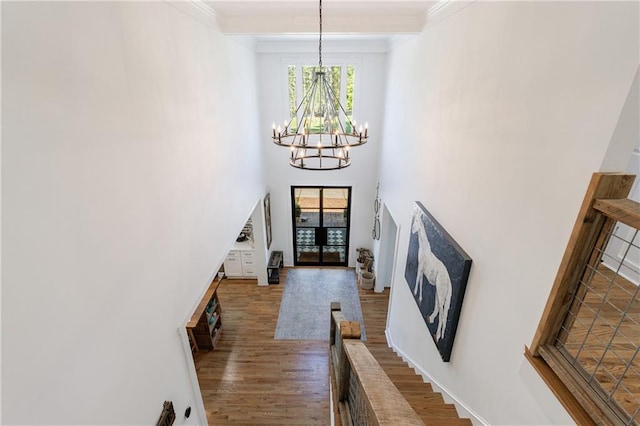 entryway with beamed ceiling, a notable chandelier, stairs, a towering ceiling, and wood finished floors