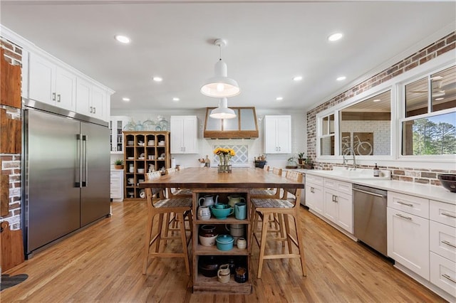kitchen with a sink, stainless steel appliances, custom range hood, backsplash, and white cabinets