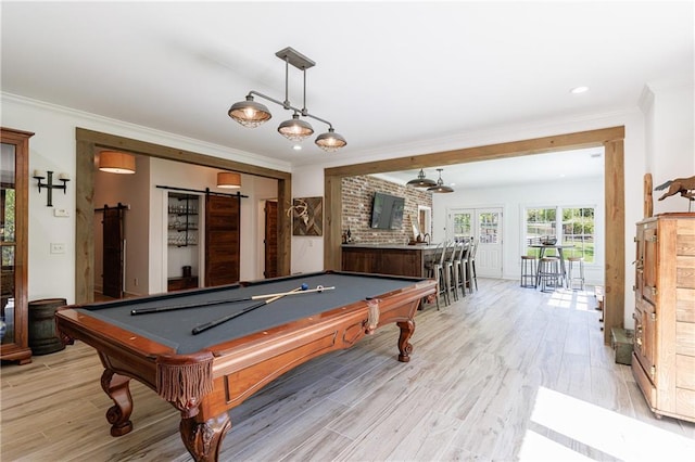 recreation room with a barn door, light wood-style floors, ornamental molding, and pool table