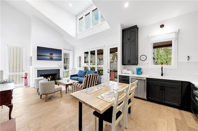 10862 Serenbe Ln, Chattahoochee Hills, GA 30268 - kitchen featuring dishwasher, dark cabinetry, light wood-style floors, light countertops, and a towering ceiling