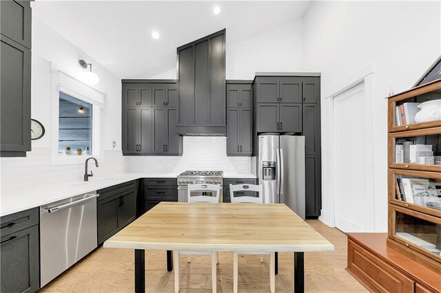 10862 Serenbe Ln, Chattahoochee Hills, GA 30268 - kitchen with stainless steel appliances, vaulted ceiling, custom range hood, light countertops, and light wood finished floors