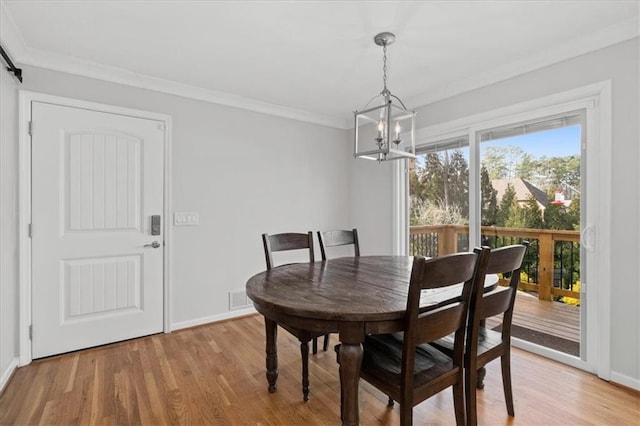 dining area featuring ornamental molding, a chandelier, and light hardwood / wood-style flooring