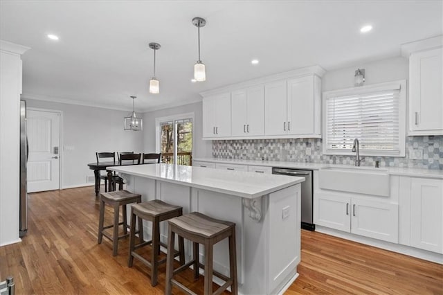 kitchen with sink, stainless steel dishwasher, a center island, and white cabinets