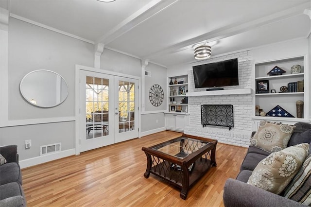 living room with beamed ceiling, ornamental molding, built in features, and french doors