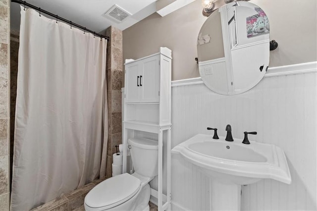 bathroom featuring walk in shower, toilet, and sink