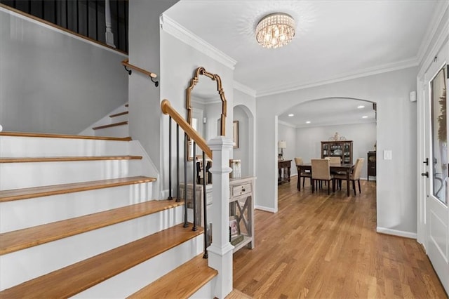 foyer entrance with ornamental molding, a notable chandelier, and light wood-type flooring