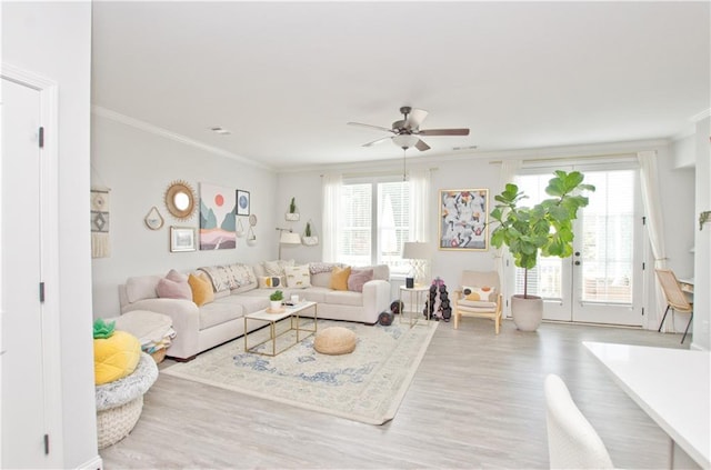 living area featuring ornamental molding, a healthy amount of sunlight, ceiling fan, and wood finished floors