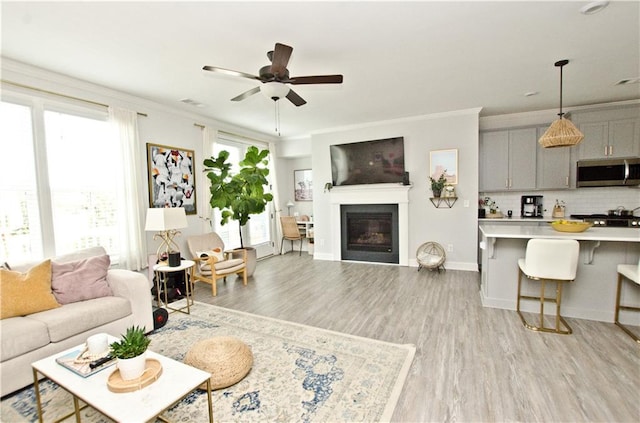 living room with light wood finished floors, a wealth of natural light, and crown molding