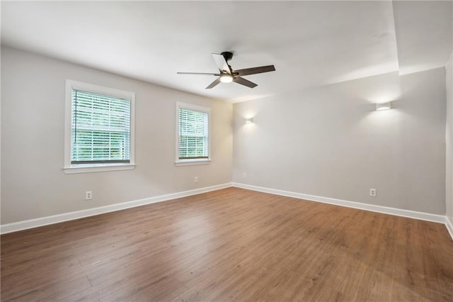 empty room featuring baseboards, a ceiling fan, and wood finished floors