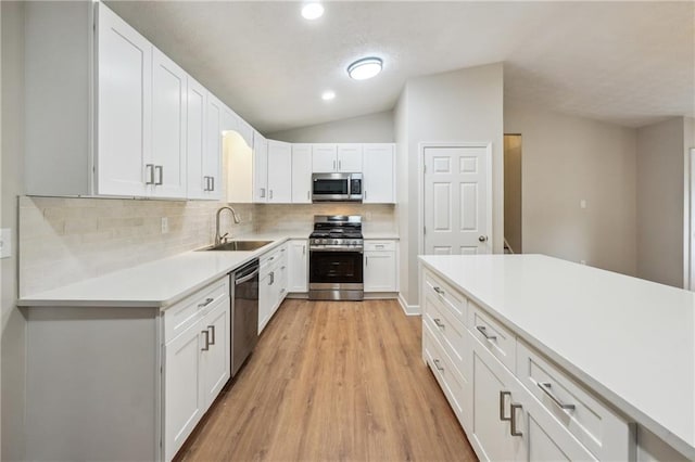kitchen featuring a sink, light countertops, light wood-style flooring, stainless steel appliances, and decorative backsplash