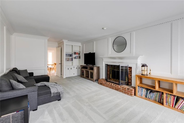 carpeted living room with built in shelves, ornamental molding, a fireplace, and a decorative wall