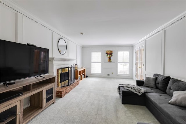 living area with light colored carpet, ornamental molding, a fireplace, and a decorative wall