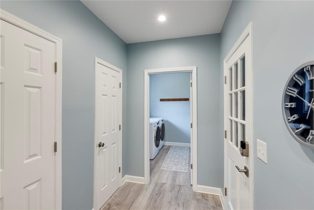 laundry area with washing machine and clothes dryer, laundry area, light wood finished floors, and baseboards