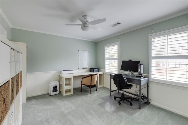 home office featuring visible vents, light colored carpet, ornamental molding, and a ceiling fan