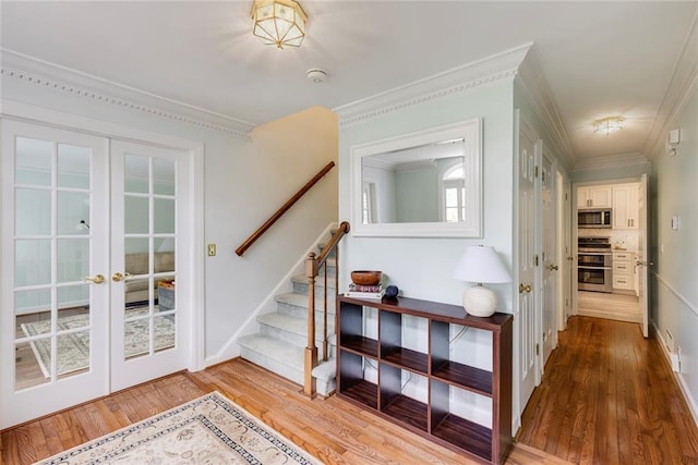 interior space with wood finished floors, french doors, baseboards, and ornamental molding