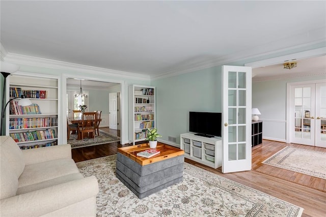 living area featuring visible vents, baseboards, ornamental molding, french doors, and wood finished floors